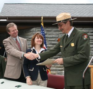 During the 2011 dedication of the new Oconaluftee Visitor Center, Maddox shakes the hand of his colleague, former park superintendent Dale Ditmanson, while long-time GSMA board of directors’ chairperson Barbara Muhlbeier hands over signed papers transferring ownership of the building from GSMA to Great Smoky Mountains National Park. Provided by Great Smoky Mountains Association.