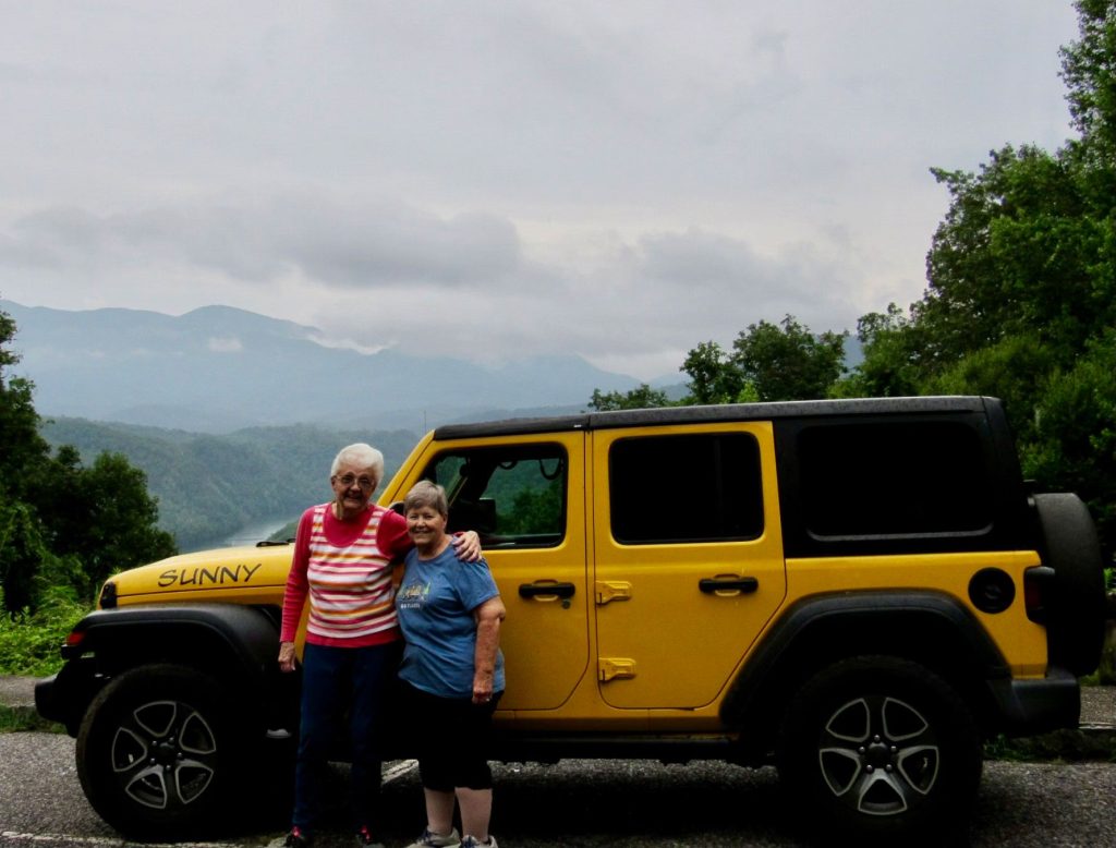 Carol Treiber and Alice Ann Sargeant next to the yellow jeep.
